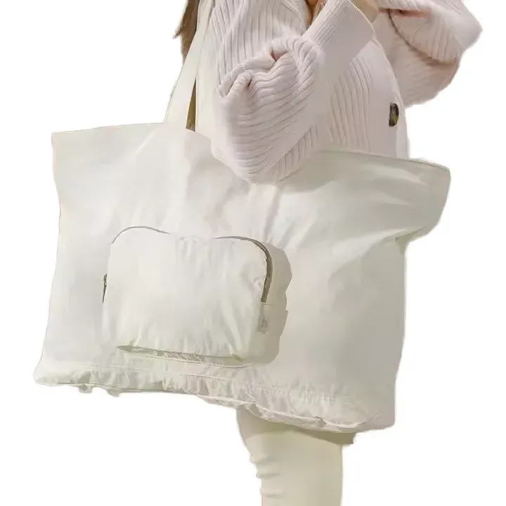 Woman carrying cream white foldable travel tote over shoulder, lightweight gym and overnight bag